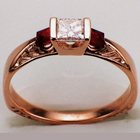 Hand-engraved 14 karat rose gold knife-edge saddle ring with a princess-cut diamond and two princess-cut rubies.