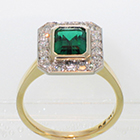 18 Karat and Platinum "halo" ring with Emerald in full-bezel setting and bead-set diamonds on halo plate around emerald