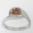 Platinum Asymmetrical wrap-around solitaire with channel-set oval-shaped natural orange-colored diamond