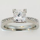 Platinum ring with Princess-cut diamond in 4-prong setting and bead-set melee round diamonds on pinched shank