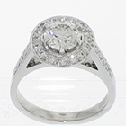 Platinum "halo" ring with round brilliant diamond in 6-prong setting above bead-set round plate with bead-set diamonds on cathedral-style shank