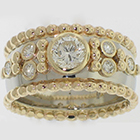 Platinum half-round tapered band with 18 Karat Yellow Gold beaded borders and bezel-set round diamonds with bead accents