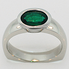 Palladium ring with oval-shaped emerald in bezel setting.