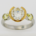 Platinum ring with 2 carat round brilliant yellow diamond in 18 karat yellow gold bezel with fancy intense yellow pear-shaped diamonds on the sides.