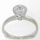 Platinum ring with irradiated colored diamonds flush-set into sides of center round brilliant diamond bezel setting