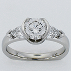 Platinum diamond ring with round brilliant in semi-bezel and crescent shield-cut diamonds on sides.