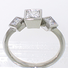 Platinum 3-stone ring with princess-cut diamonds set in full bezels on knife-edge band