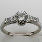 platinum ring with 0.74 carat round brilliant center diamond in semi-bezel and 0.38 carat total weight(0.19 ct. each) tapered brilliant baguettes.