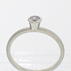 Platinum stacker ring with 0.18 carat round brilliant diamond in full high-profile polished bezel on brushed half-round band