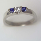 platinum ring with princess-cut diamond in saddle and two princess-cut sapphires set with triangular bars
