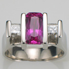 Platinum ring with channel-set cushion-cut pink sapphire and two princess-cut diamonds.