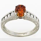 Hand-engraved platinum diamond ring with natural orange center and channel-set round sides.