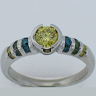 Platinum diamond ring with yellow center and blue green and yellow diamond channels.