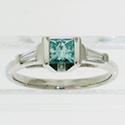 Platinum 3-stone ring with irradiated blue princess-cut diamond channel-set in angled saddle setting with tapered step-cut baguettes (alternate view)