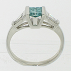 Platinum 3-stone ring with irradiated blue princess-cut diamond channel-set in angled saddle setting with tapered step-cut baguettes