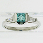 Platinum 3-stone ring with irradiated blue princess-cut diamond channel-set in angled saddle setting with tapered step-cut baguettes (alternate view)
