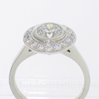 Platinum diamond ring with 1 carat round brilliant diamond in "halo" setting with round brilliant melee diamonds bead-set on halo plate