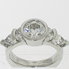 Platinum 5-stone ring with round brilliant diamond in full-bezel and channel-set crescent-moon-shaped diamonds and channel-prong-set crescent-shield-shaped diamonds