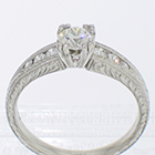 Platinum hand-engraved ring with 0.54 carat round nrilliant diamond in fancy fishtail setting and 6 side stones in tapered channel
