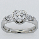 Platinum diamond ring with round brilliant in semi-bezel and crescent shield-cut diamonds on sides.