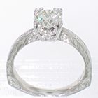 Platinum hand-engraved solitaire with 1 carat round brilliant diamond set in 12-prong fishtail-style fancy head on pinched shank with corners