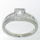 Platinum engagement ring with 0.53 carat princess-cut diamond in bezel setting on hand-engraved tapered-channel shank with 0.24 carat total weght of round melee diamonds