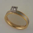 platinum + 18 karat yellow gold band with princess-cut diamond in tapered full bezel.