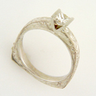 platinum hand-engraved high-top ring with corners in back for self-straightening and v-shaped saddle with princess-cut diamond